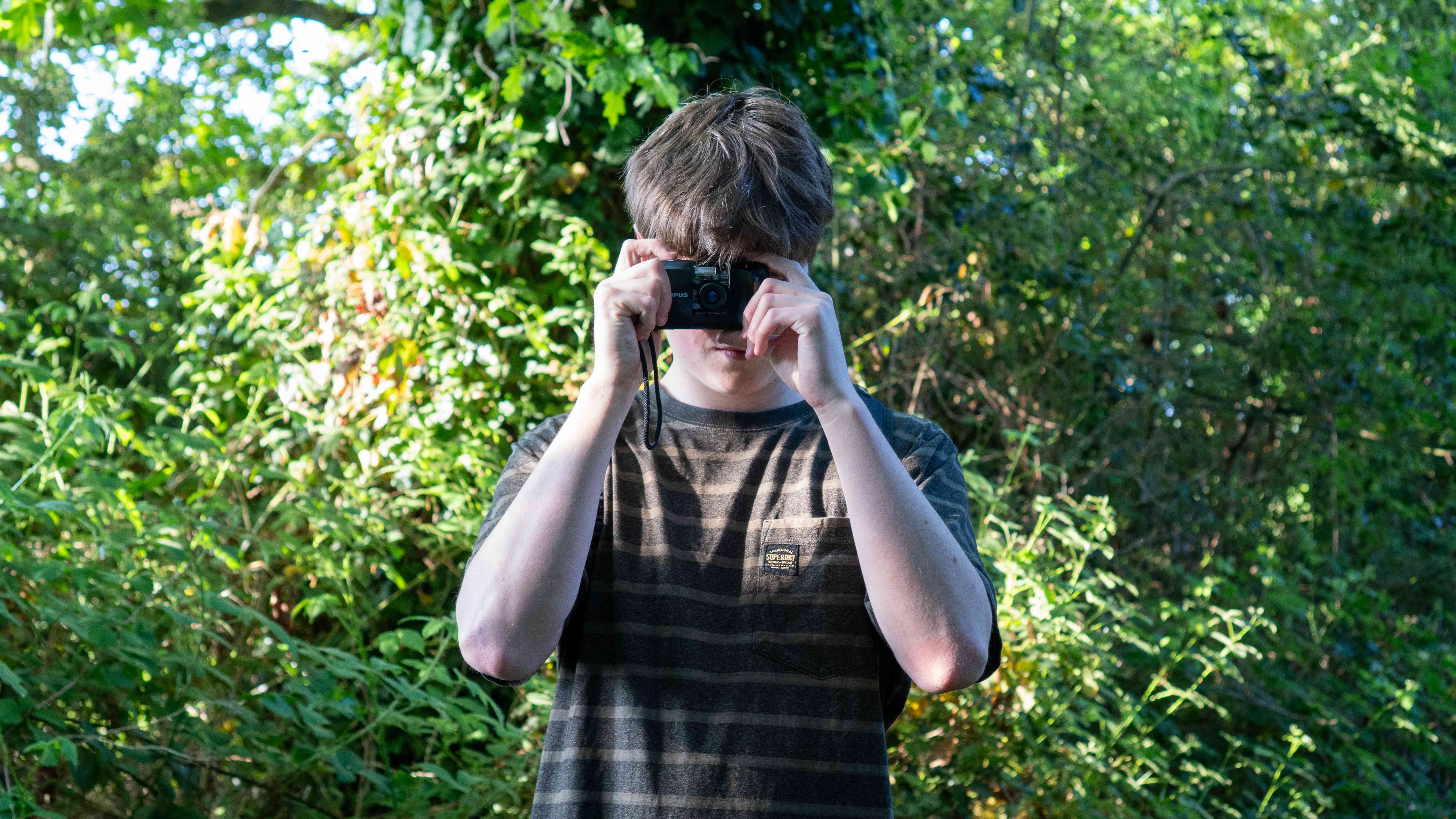 Charlie Milner holding a film camera outdoors